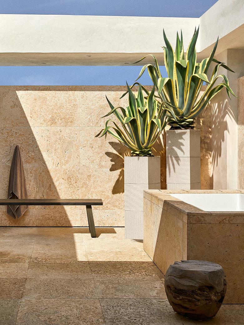 Two Apollo planters of variegated agaves on a limestone rooftop terrace beside an outdoor tub