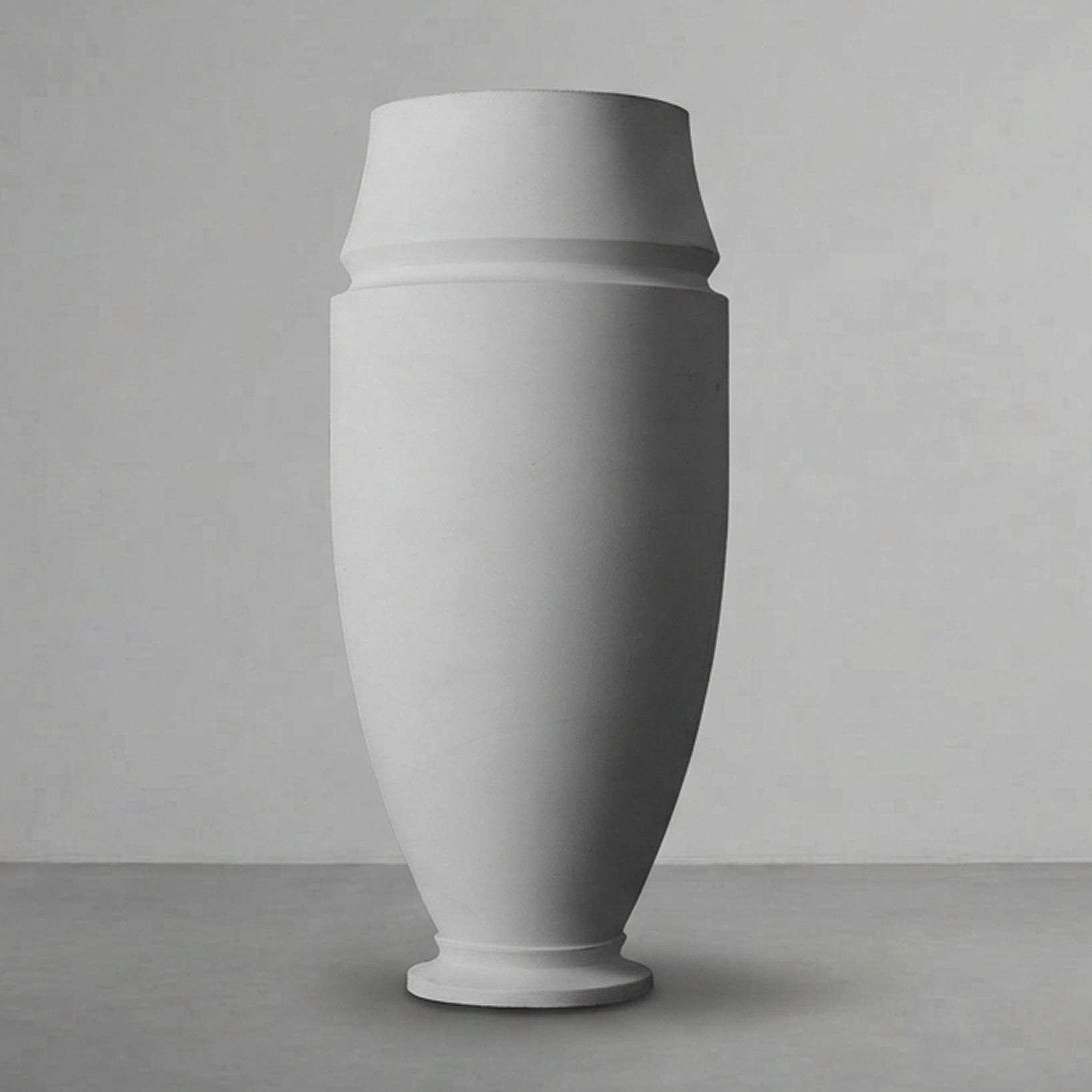 Artifact 06 in Alabaster, a tall slender vase form, on a grey studio backdrop