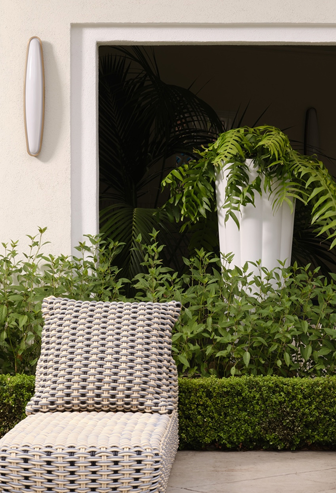 A Byblos planter of ferns beside a garden doorway and woven seating