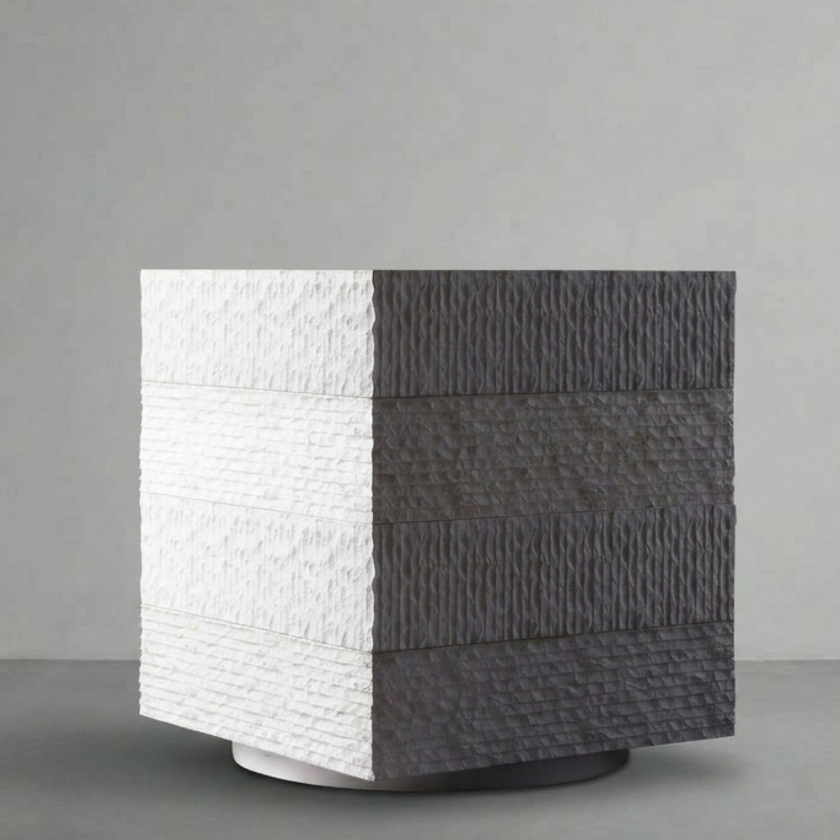 Janus IV, the largest cube, split white and charcoal, on a grey studio backdrop